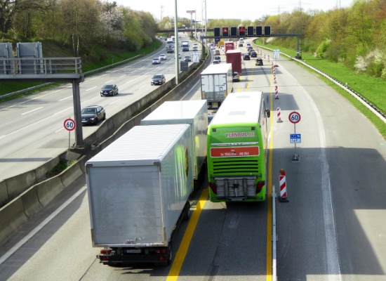 Zwei große Fahrzeuge, hier Lkw mit einem ausscherenden Anhänger und ein voll besetzter Reisebus, der rechts überholt. Gefährlich nahe kommen sich beide, keine 5 cm Abstand bei über 60 km/h